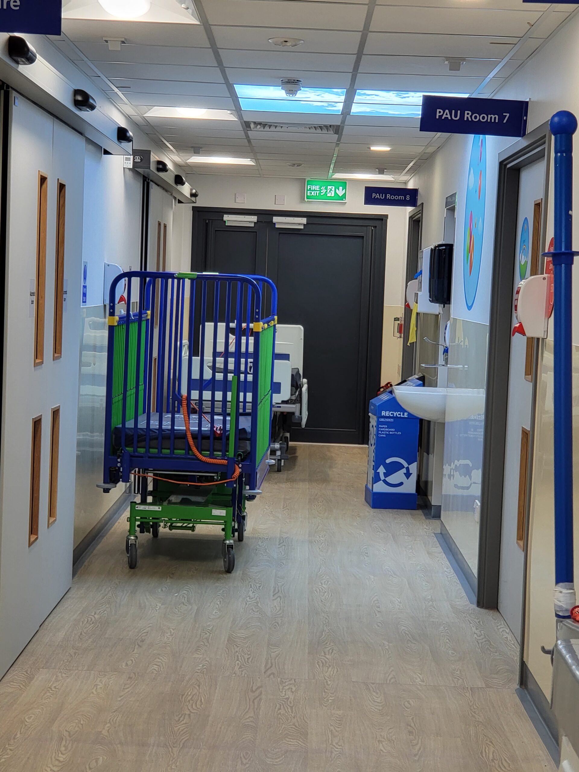 A hospital hallway with two beds and a sink.
