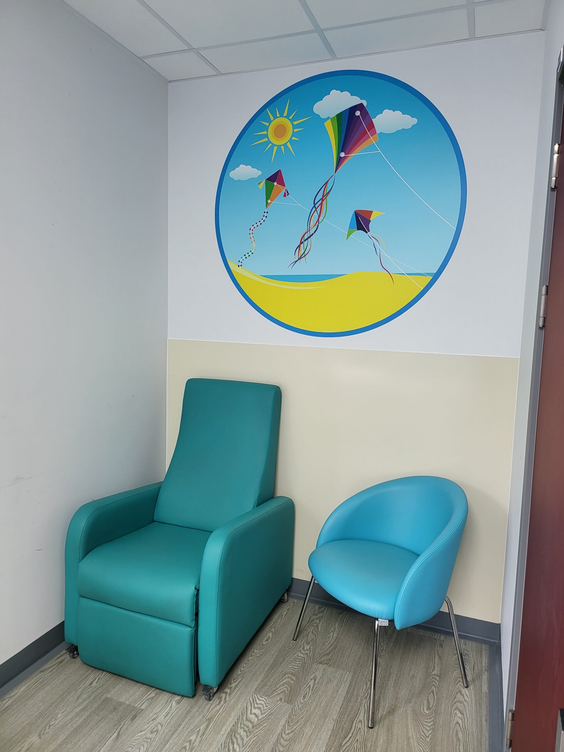 A room with a blue chair and a mural of kites.