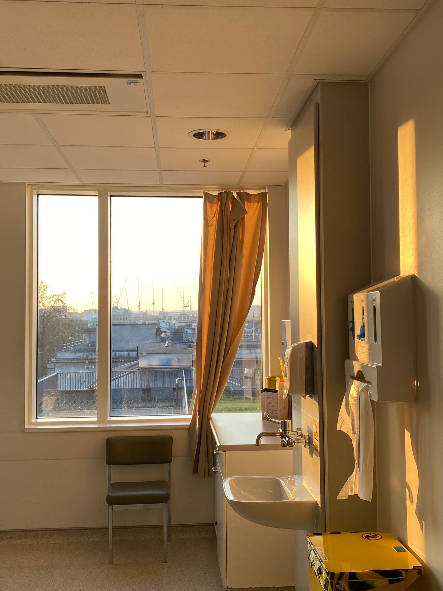A hospital room with a window and a sink.