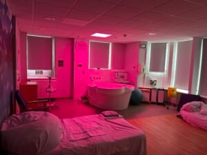 A room with a bed, a bedside table, and a bathtub.