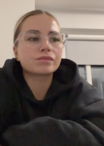 A woman in a black hoodie with glasses.